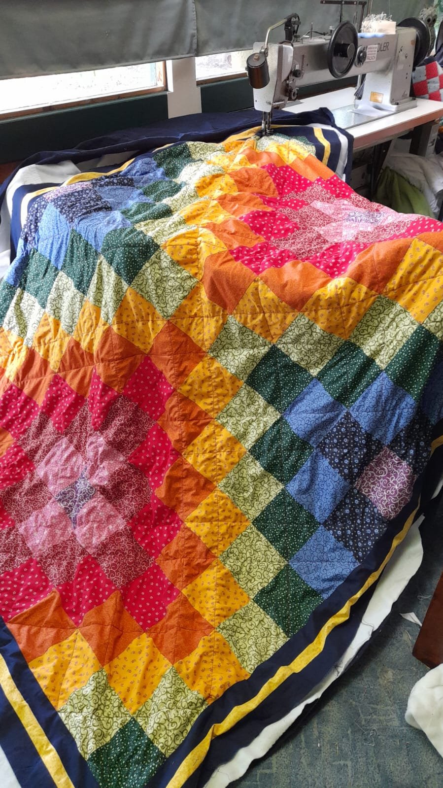 Bunte Patchworkdecke auf der Nähmaschine in der Werkstatt